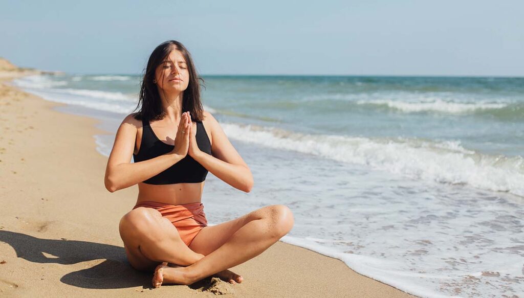 Woman meditating on a beach